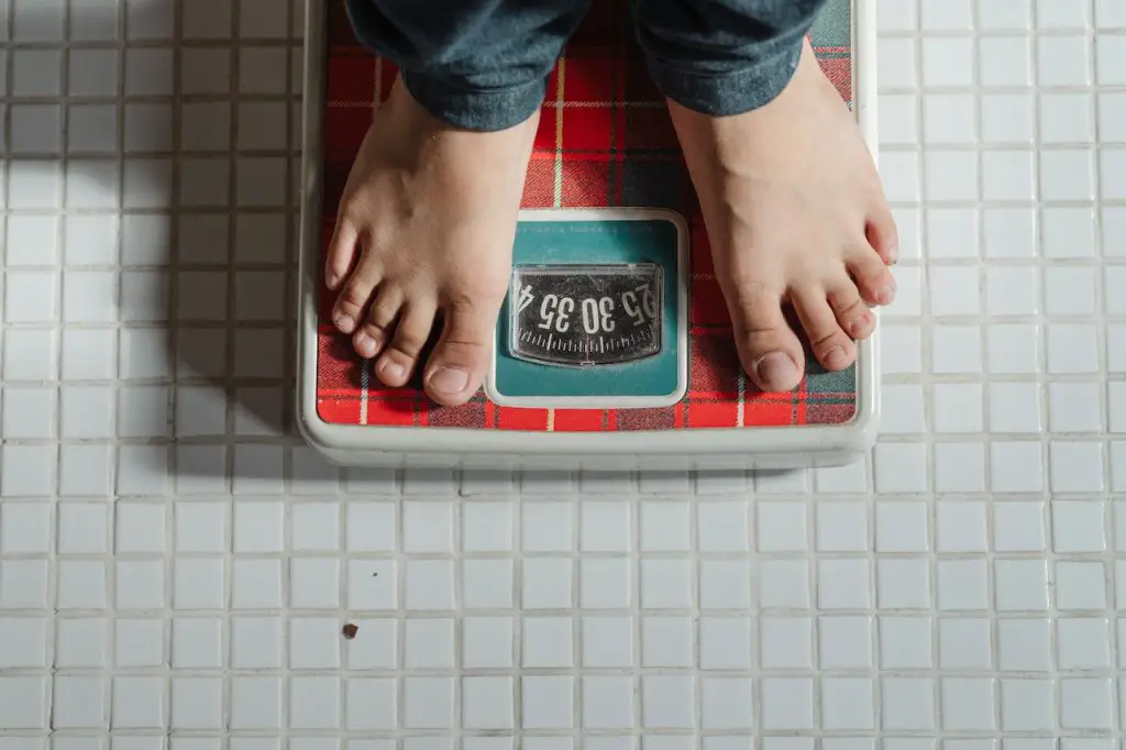 Image of a person on a red weighing scale. Source: ketut subiyanto, pexels