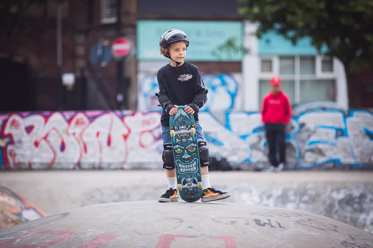 Image of a young boy wearing a protective gears while holding a skateboard. Source: riccardo parretti, pexels