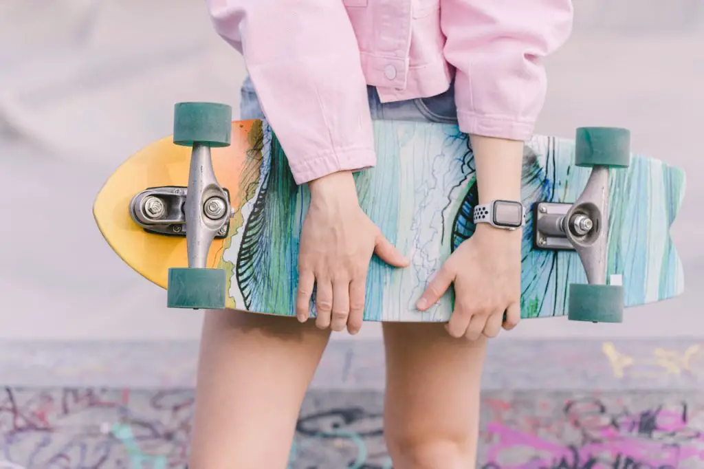 Image of someone holding a skateboard with green wheels. Source: shvets production, pexels