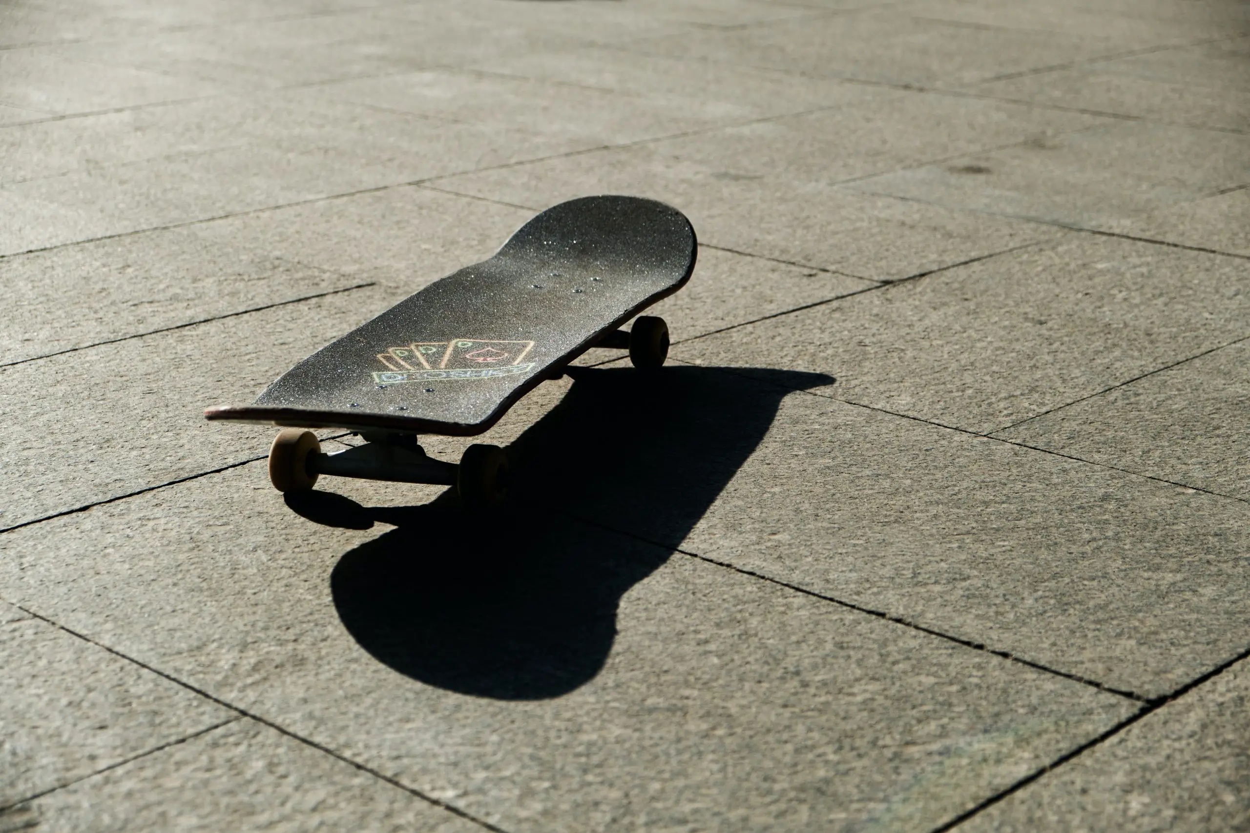 Image of a black skateboard on the floor. Source: isaac chou, unsplash