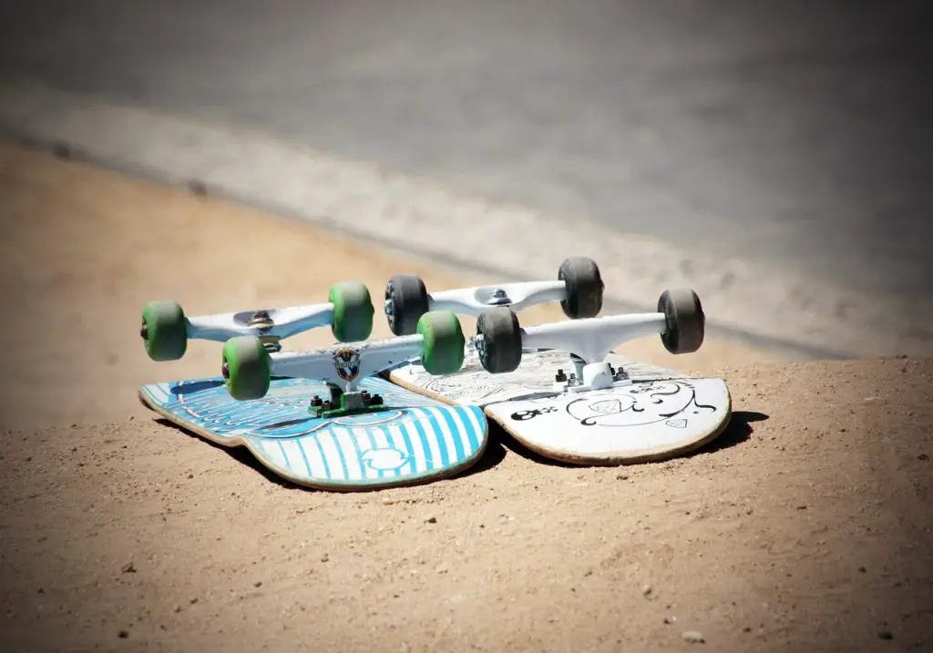 Image of two skateboards flipped over on the white sand near the sea. Source: pixabay