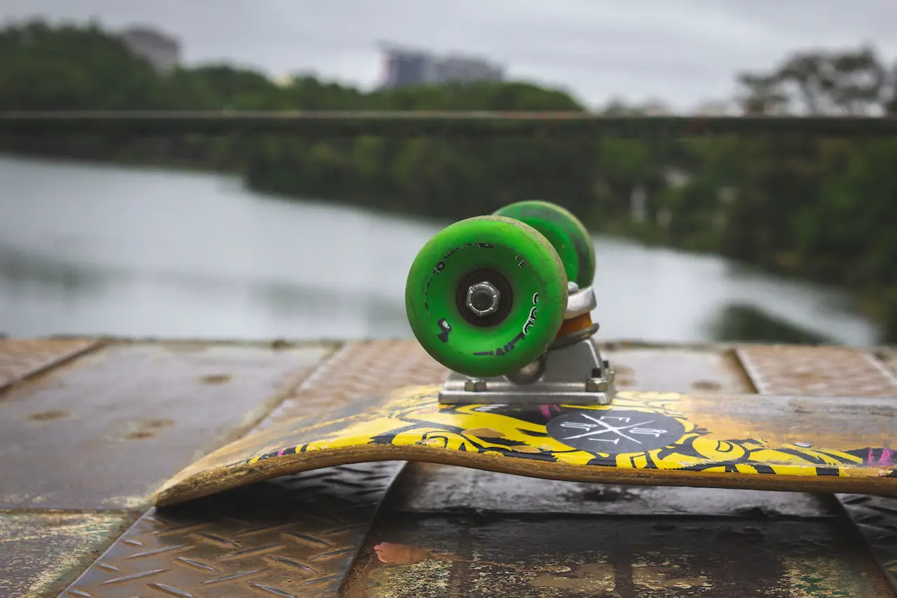 Image of a yellow designed skateboard with green skateboard wheels. Source: william eickler, pexels