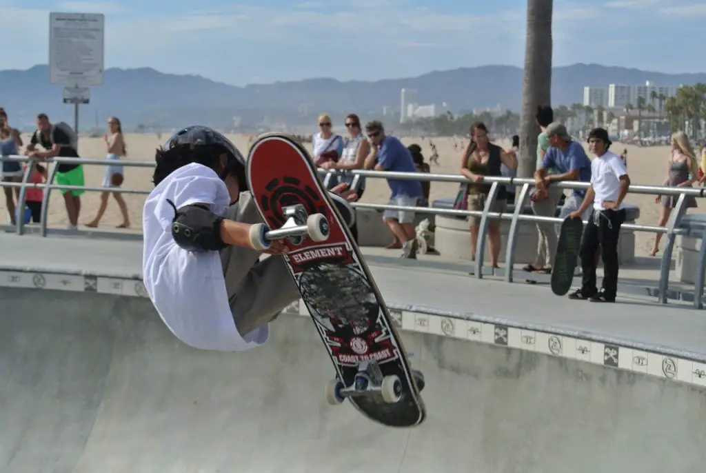 Image of a boy wearing a white shirt performing freestyle skateboarding trick in a skate park. Source: pixabay