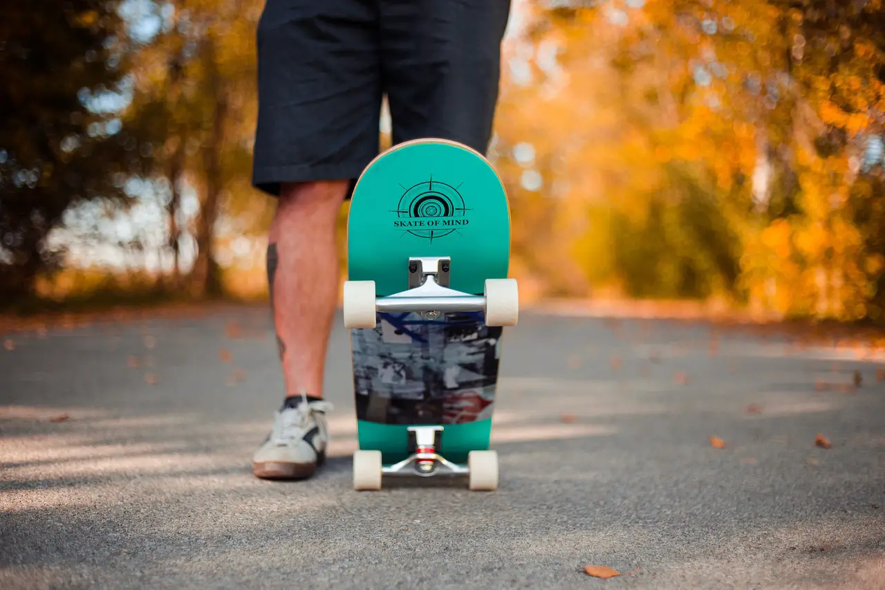 Image of a skateboarder stepping on one side of the green printed skateboard. Source: pixabay