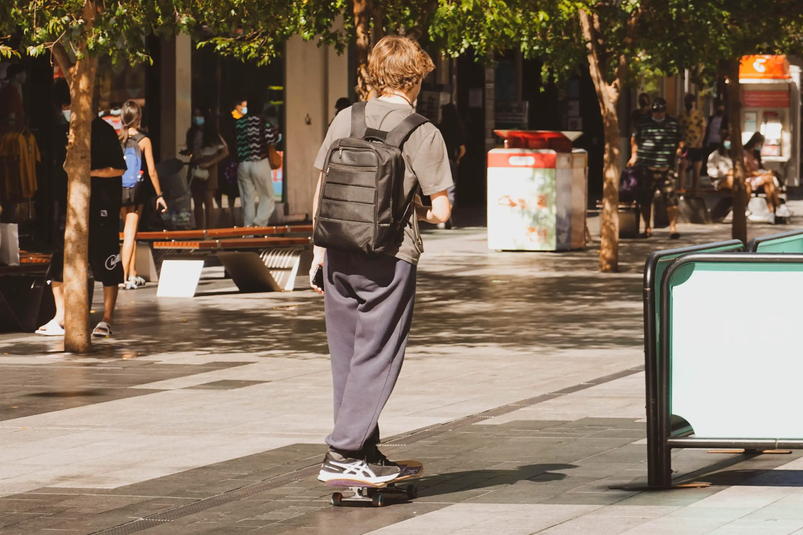 Image of a skateboarder with a black backpack skateboarding on the street. Source: unsplash