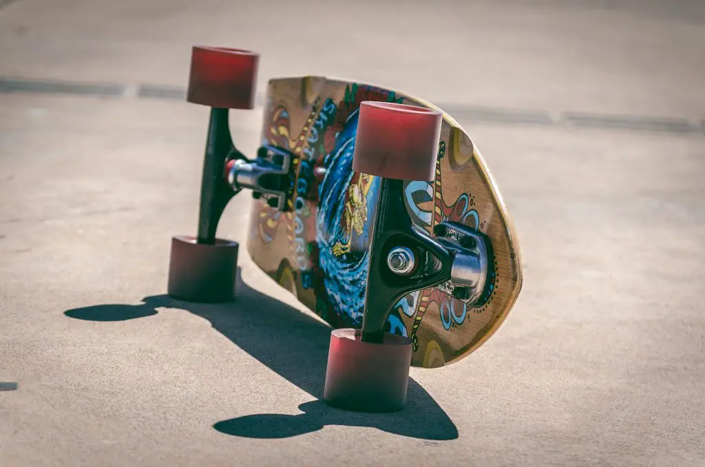 Image of skateboard lying on the side with graphic design on yellow deck and red wheels. Source: messala ciulla, pexels