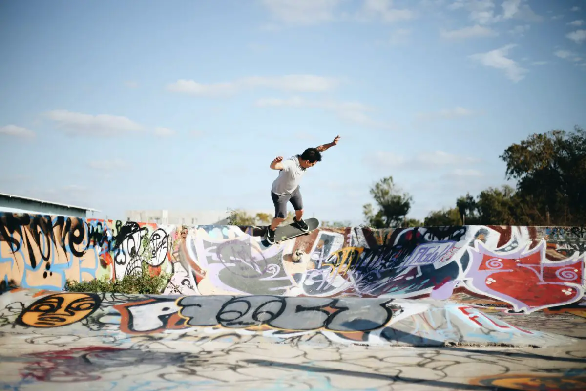 Image of a skateboarder skateboarding in a wide skate park with some skate bumps.