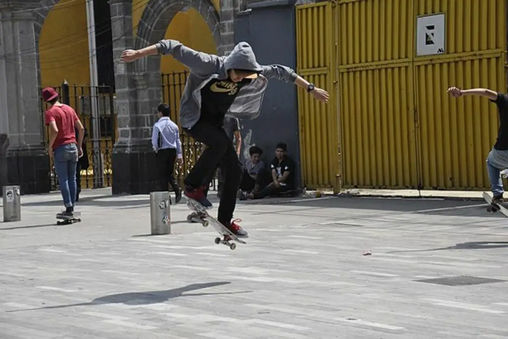 Image of a skateboarder doing ollie in the middle of a skate park.