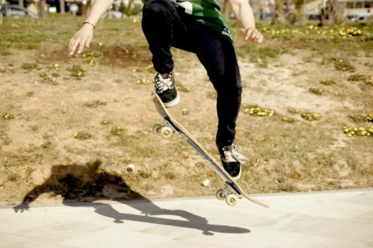 Image of a skateboarder doing ollie on the street.