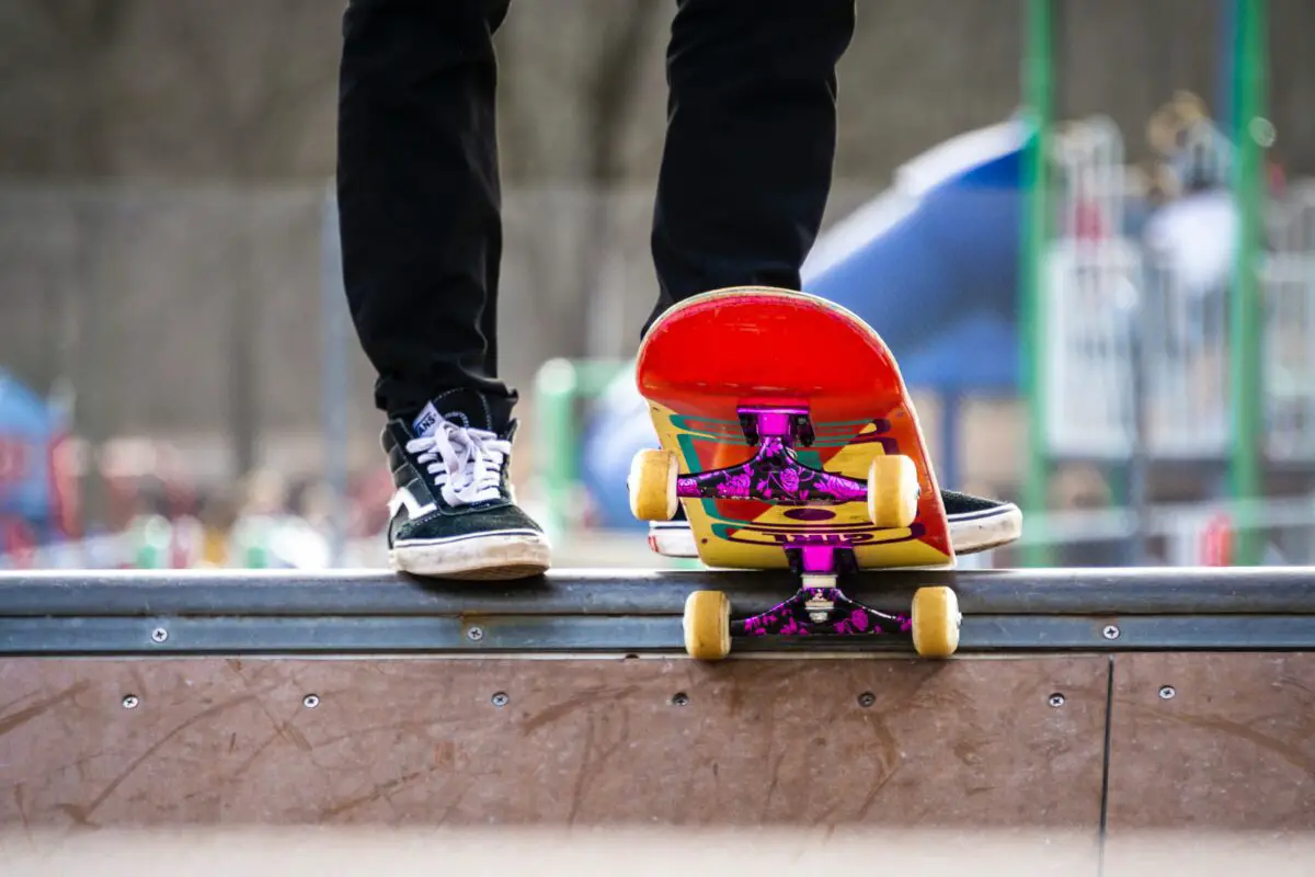 Image of a skater using a red skateboard with purple trucks and yellow wheels.