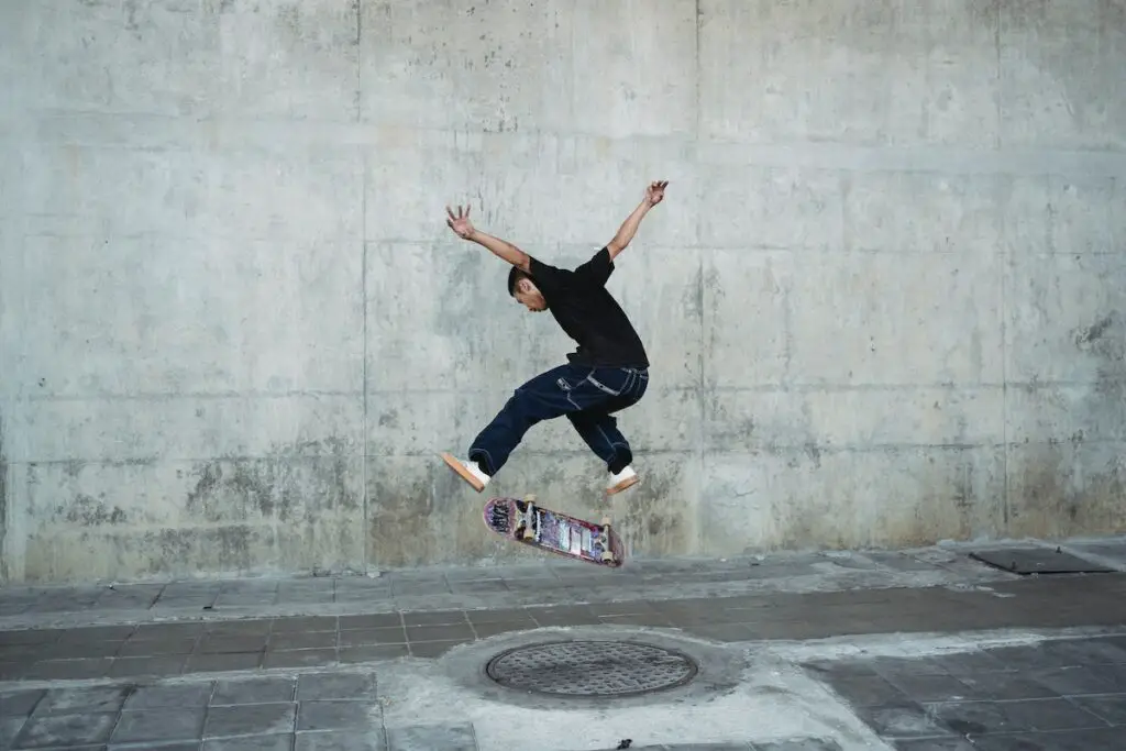 Image of a skater doing a flip skateboard trick on a concrete pavement. Source: pexels