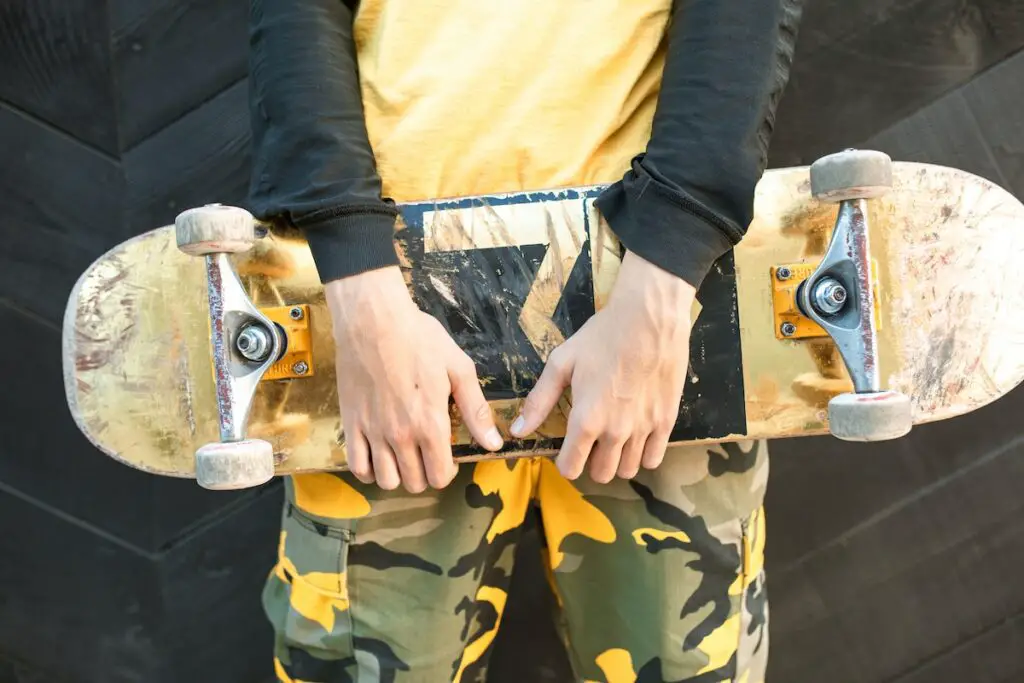 Image of a skater holding a yellow skateboard. Source: pexels