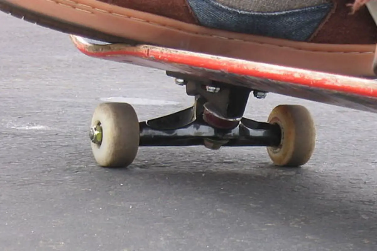 Image of a skateboard with trucks and wheels that shows usage marks. Source: wiki commons
