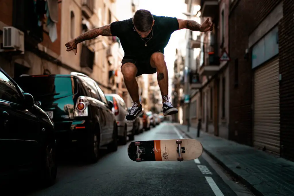 Image of a skateboarder while doing s skateboarding trick on the street.