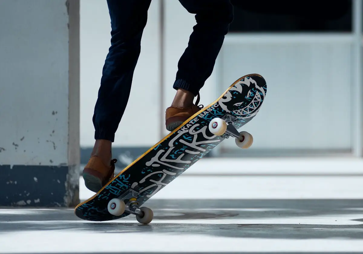 Image of a skater stepping on the skateboard tail to lift its skateboard nose. Source: pexels
