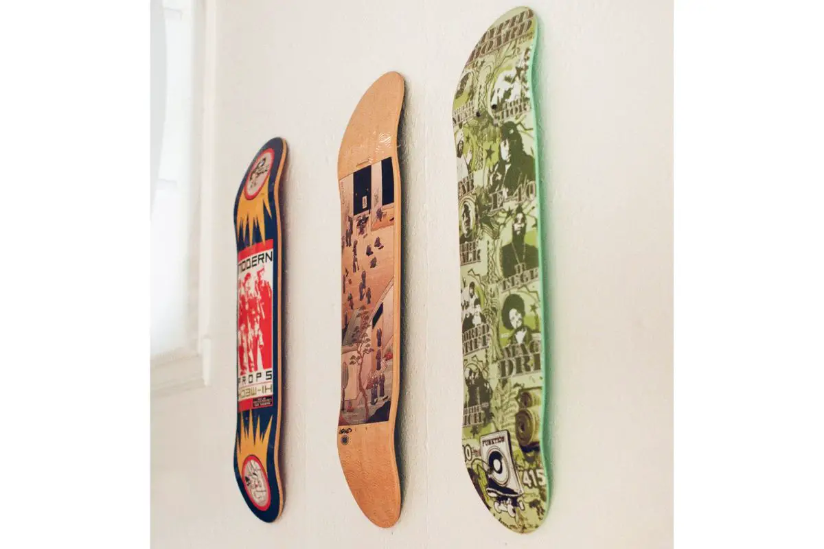 Image of three new skateboard deck with different designs hanged on a wall.