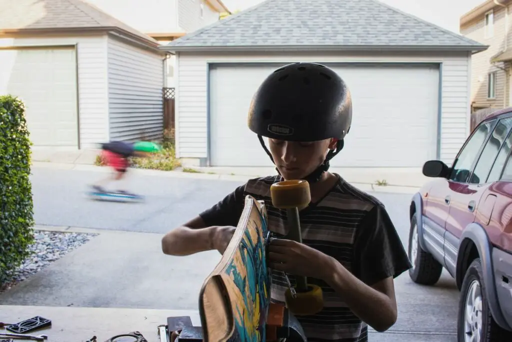 Image of a boy fixing his skateboard with tools in the garage. Source: unsplash