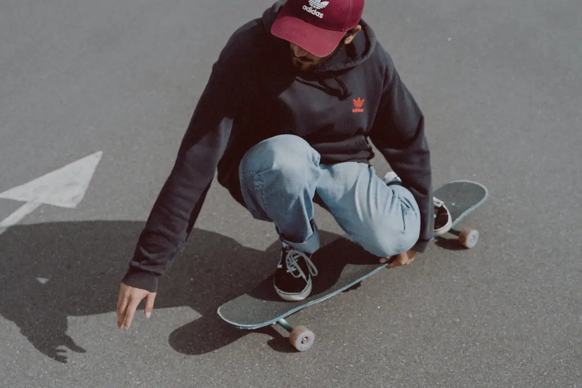Image of a skater crouching down while riding a skateboard. Source: pexels