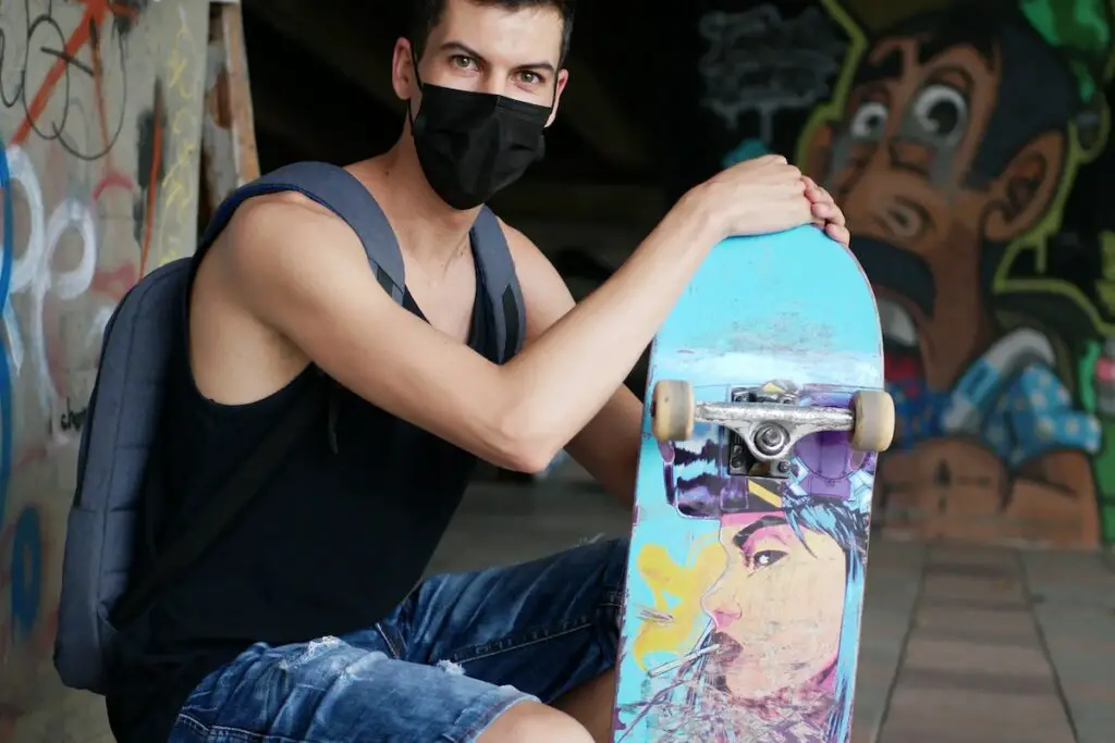 Image of a skater holding a skateboard with a facemask on. Source: pexels