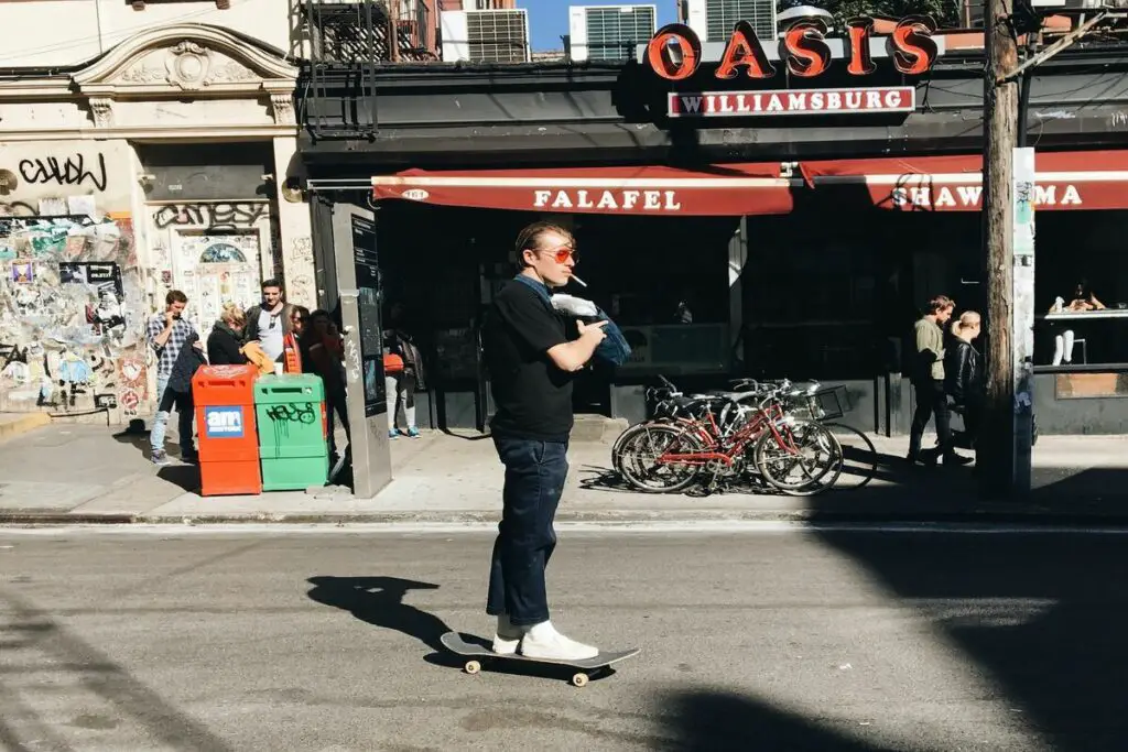 Image of a skater in the middle of the street with his skateboard and a cigarrette in his mouth. Source: unsplash