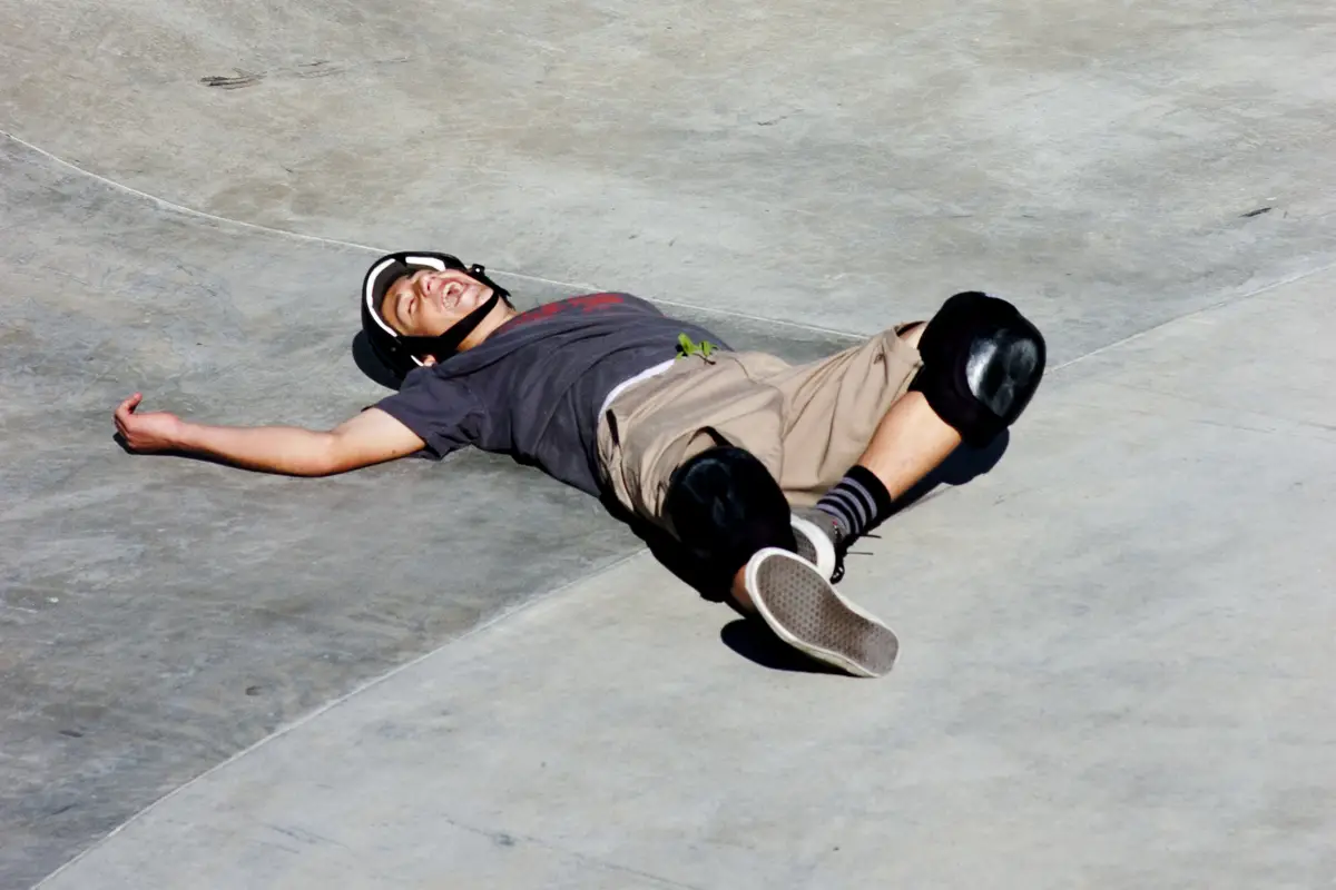 Image of an injured skater laying on the ground after falling off his skateboard. Source: wiki ccommons