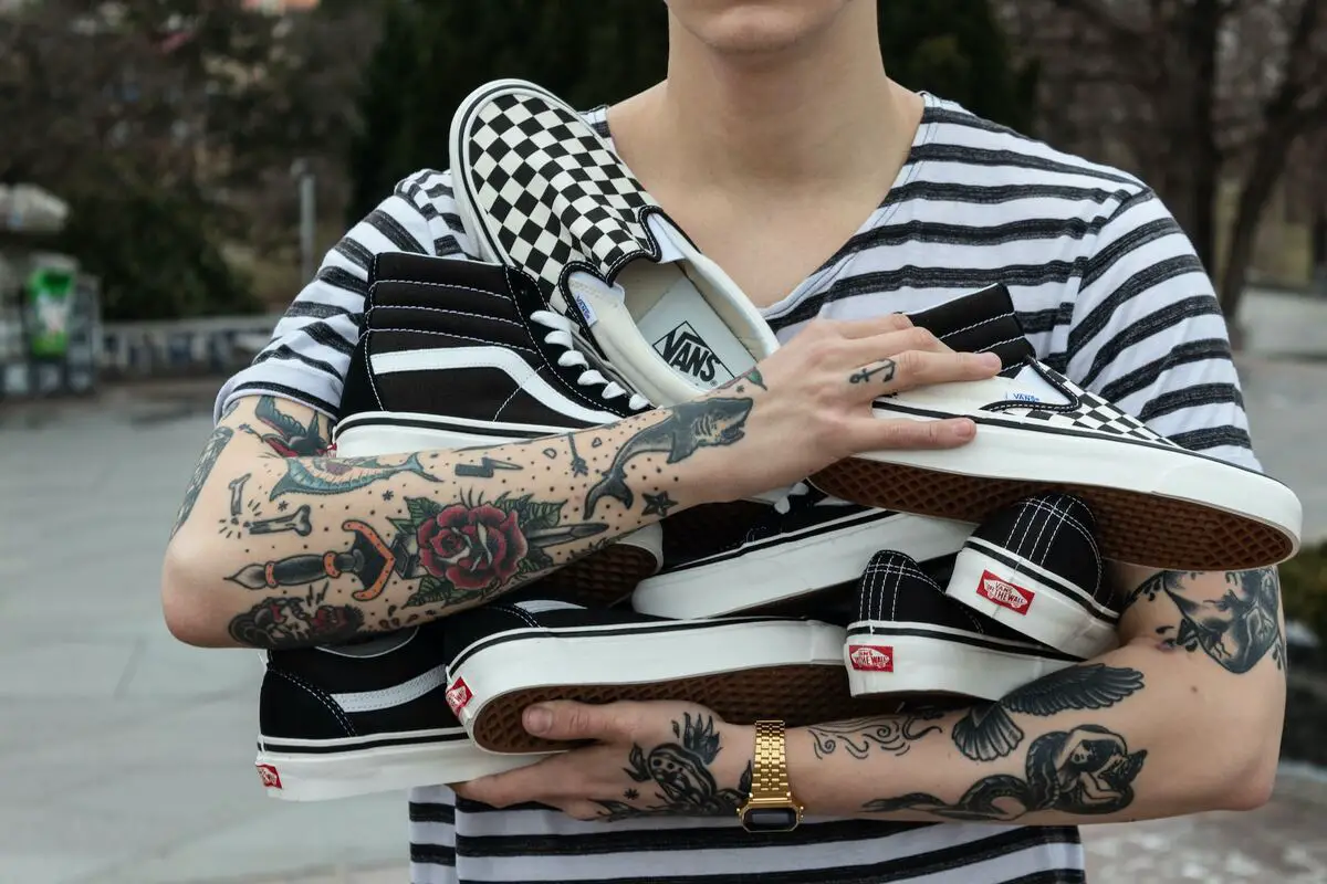 Image of a person holding vans skate shoes in his arms. Source: unsplash