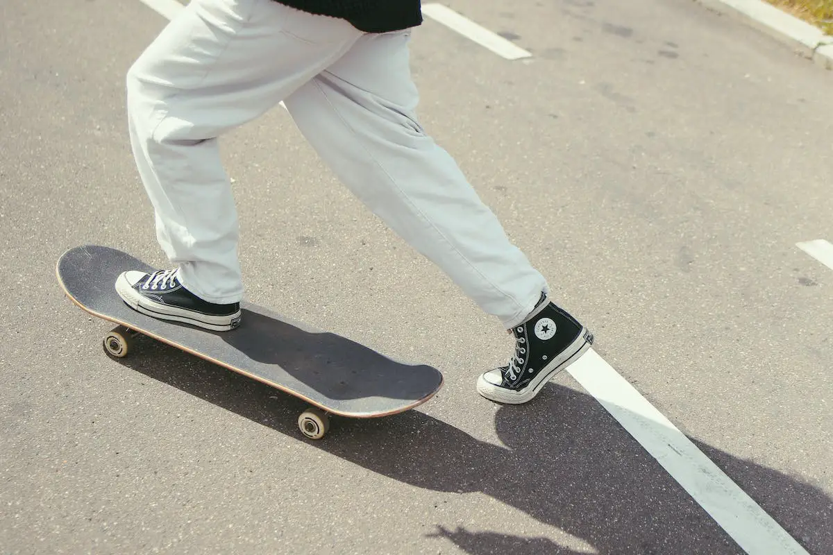 Image of a skater with black converse riding a skateboard. Source: pexels